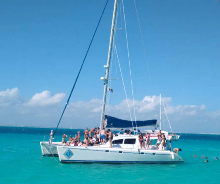 Catamarán navegando por las aguas turquesas del Mar Caribe hacia Isla Mujeres durante un tour de snorkel con Vaguemos Viajes